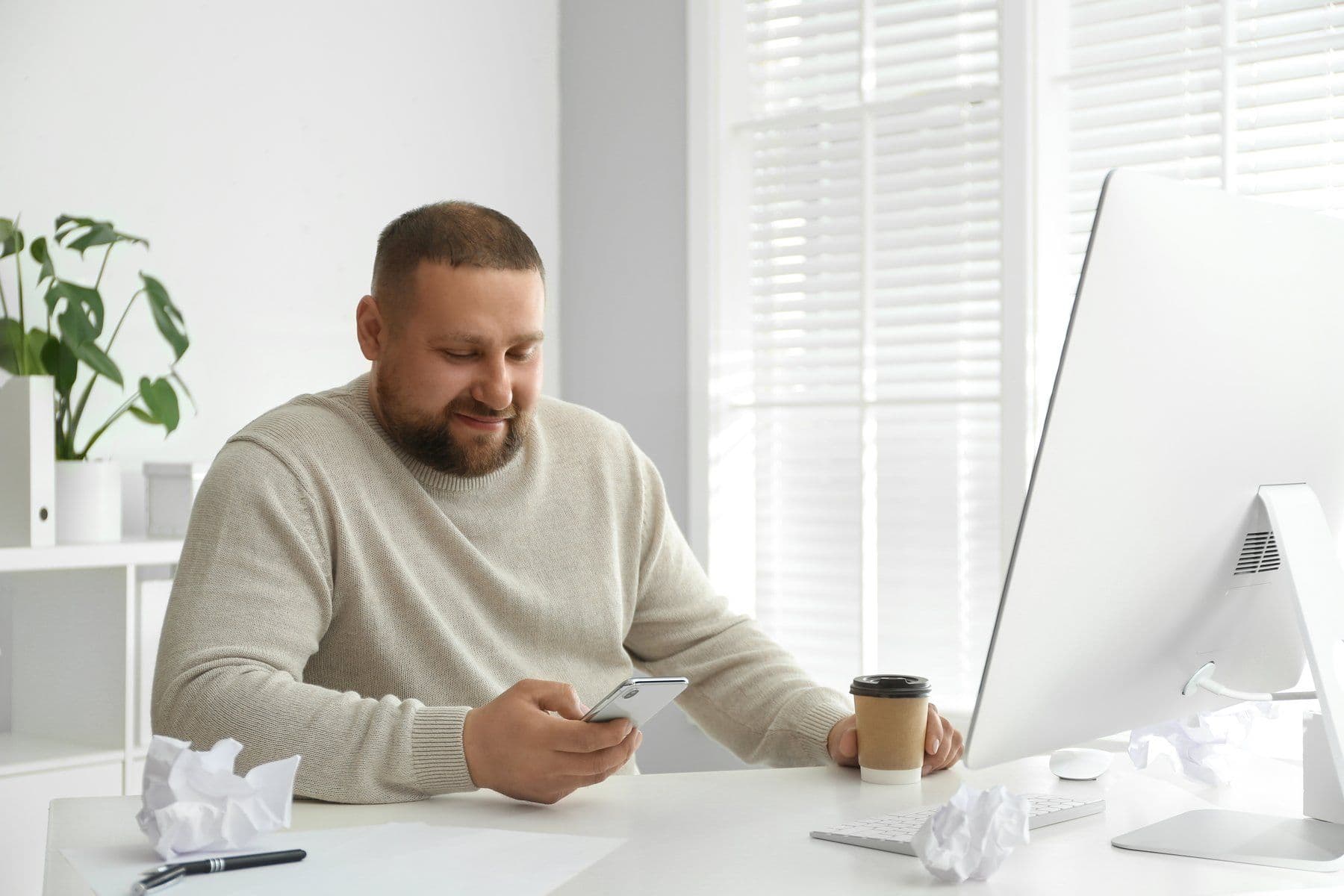 Man at his desk reading his phone