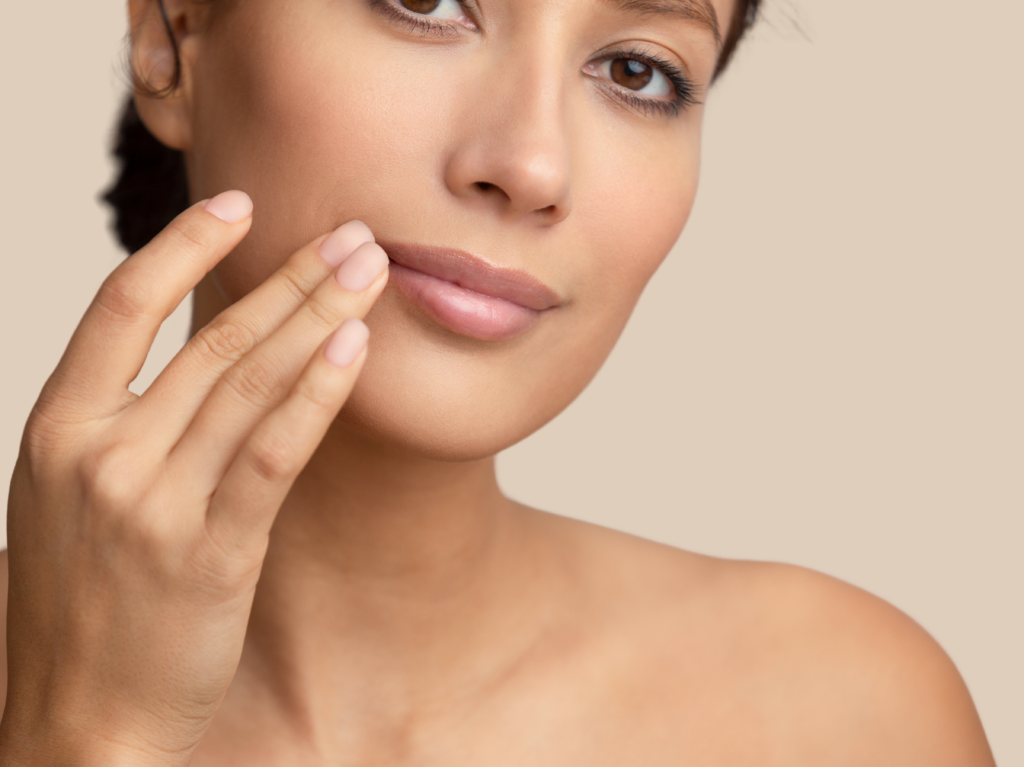 Healthy woman great skin touching side of mouth, beige background.